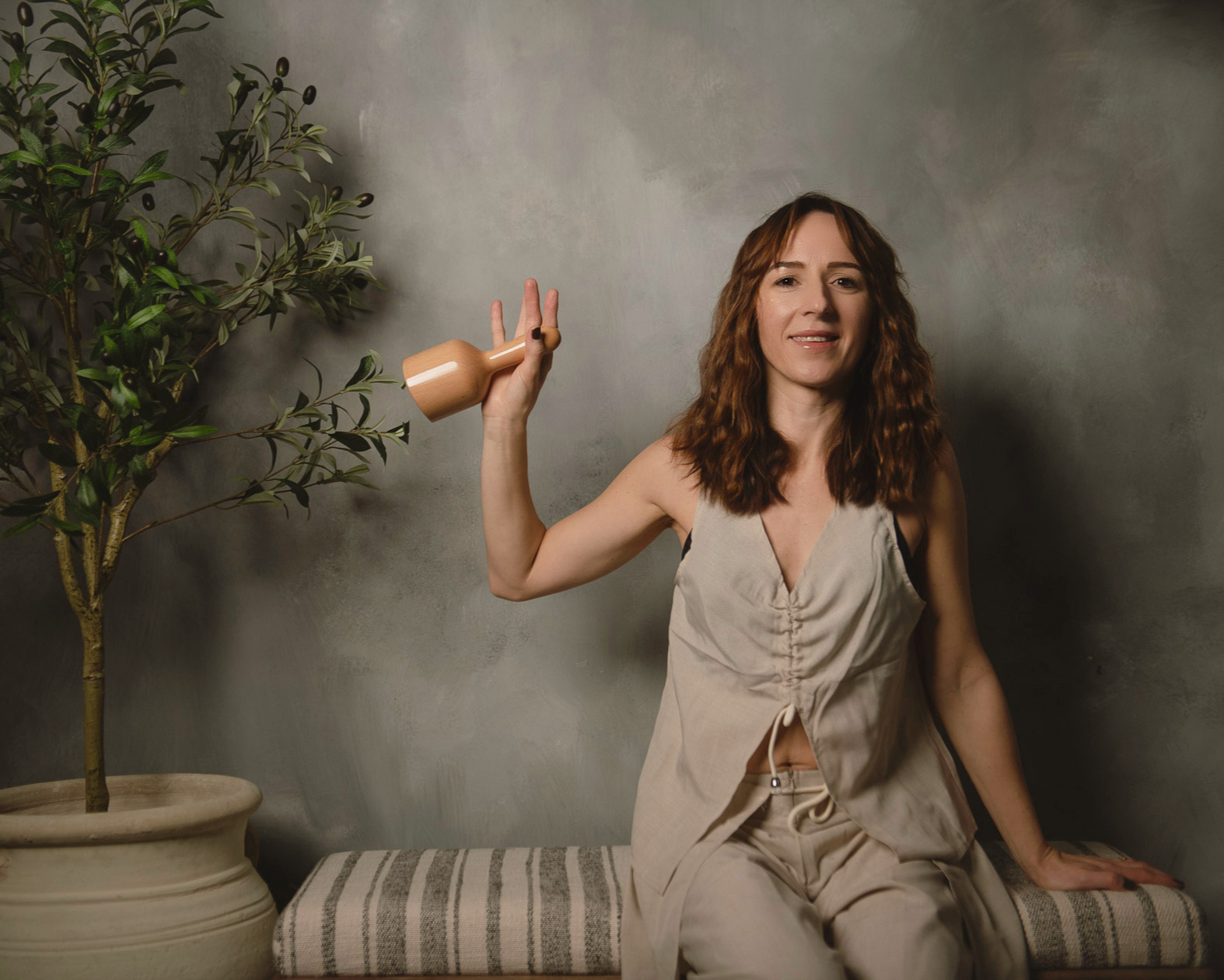 Massage therapist holding a wooden massage tool in a calm studio setting